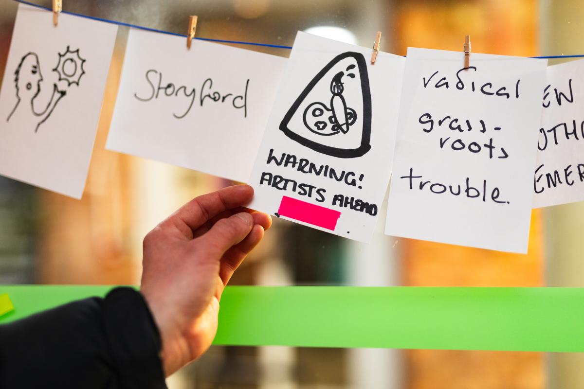 A close up of a hand and a drawing with the words Warning - artists ahead